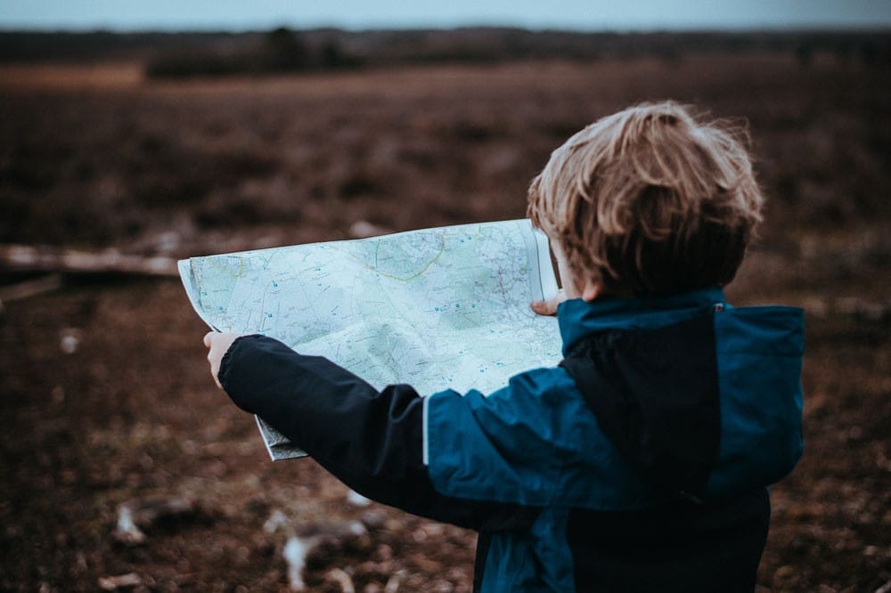 Visado familiar niño rubio con un anorak mirando un mapa