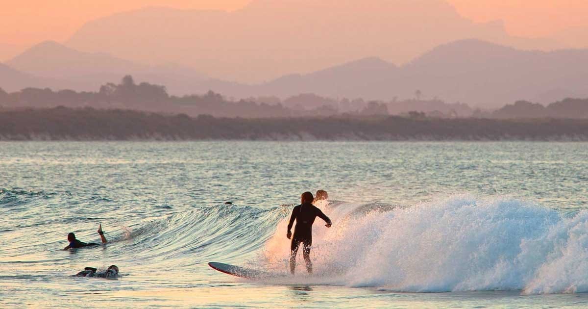Surfing australia viajar puesta de sol y un chico haciendo surf en una playa y de fondo la vegetación
