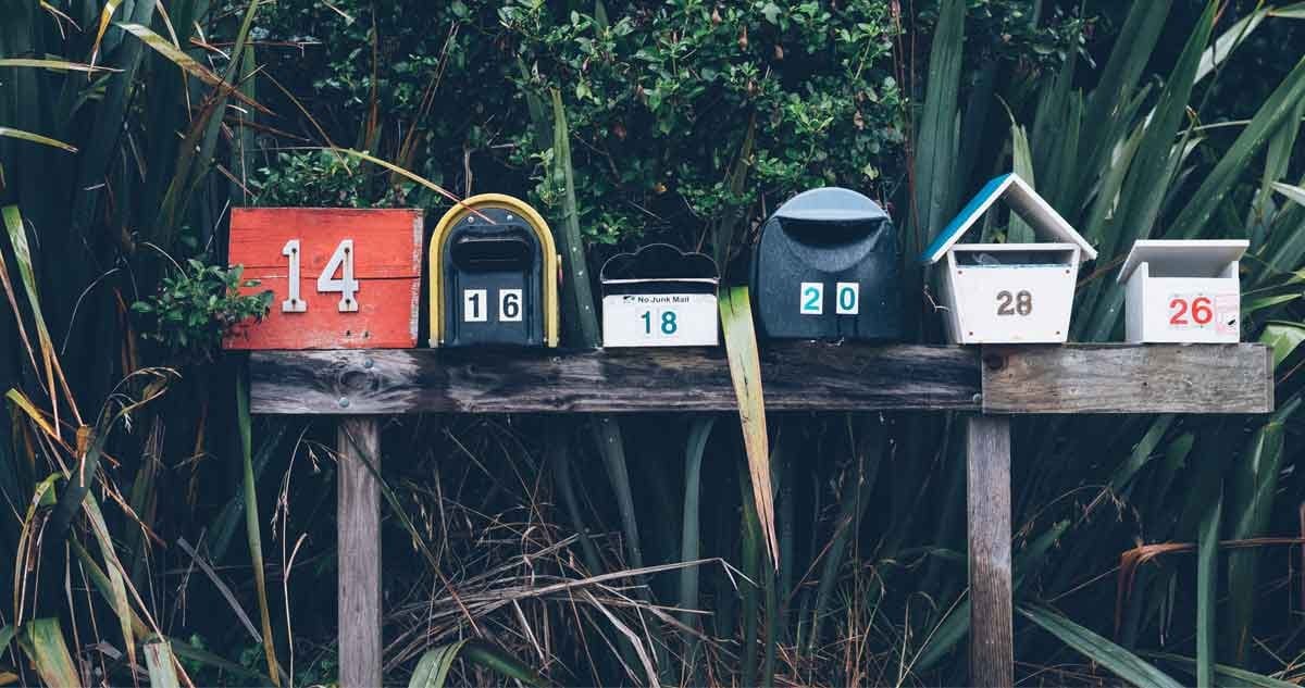 Perder pasaporte buzones de correo postal de madera y de diferentes medidas y colores encima de una madera en medio de la vegetación