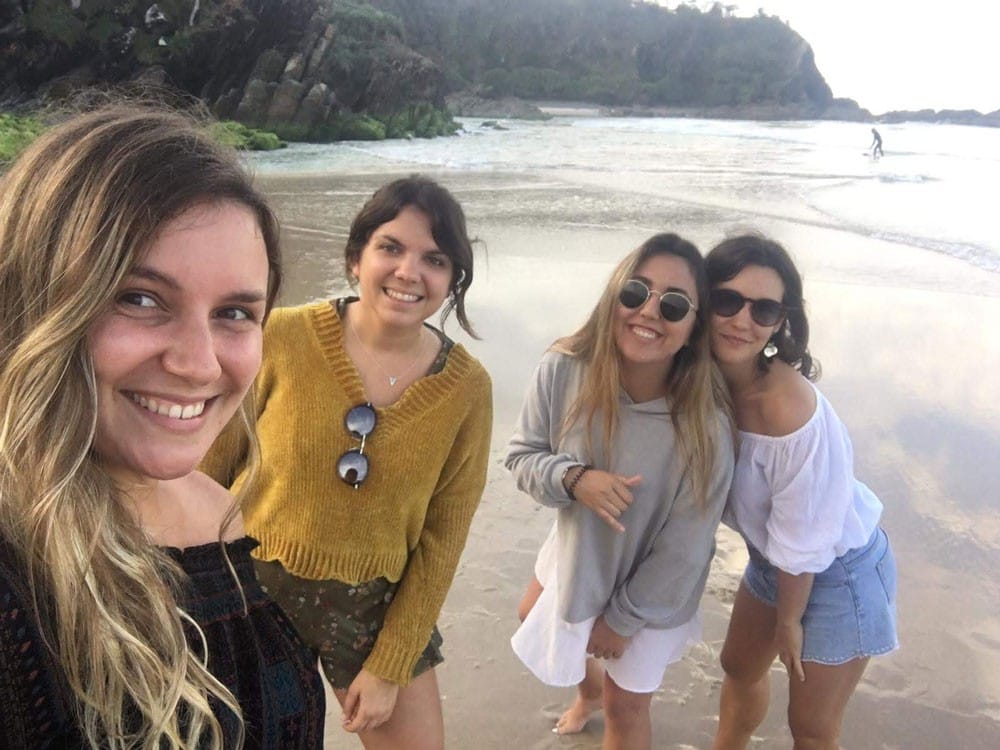 Amigas en Australia grupo de 4 chicas en la playa sonriendo a cámara