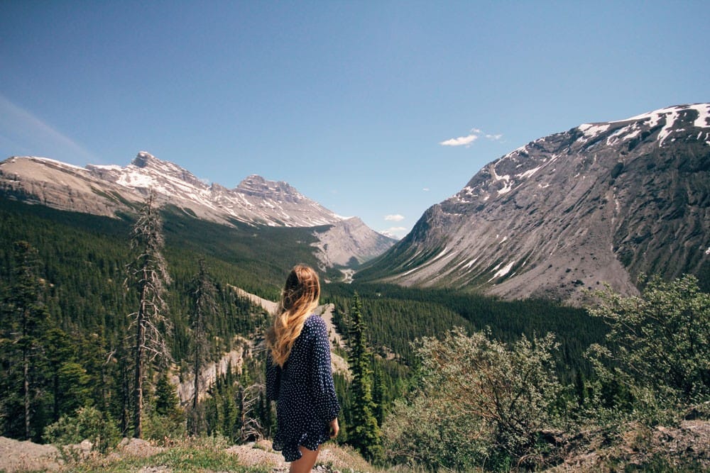 Trabajo en Canadá chica rubia de espaldas y delante el paisaje de las montañas de Canadá