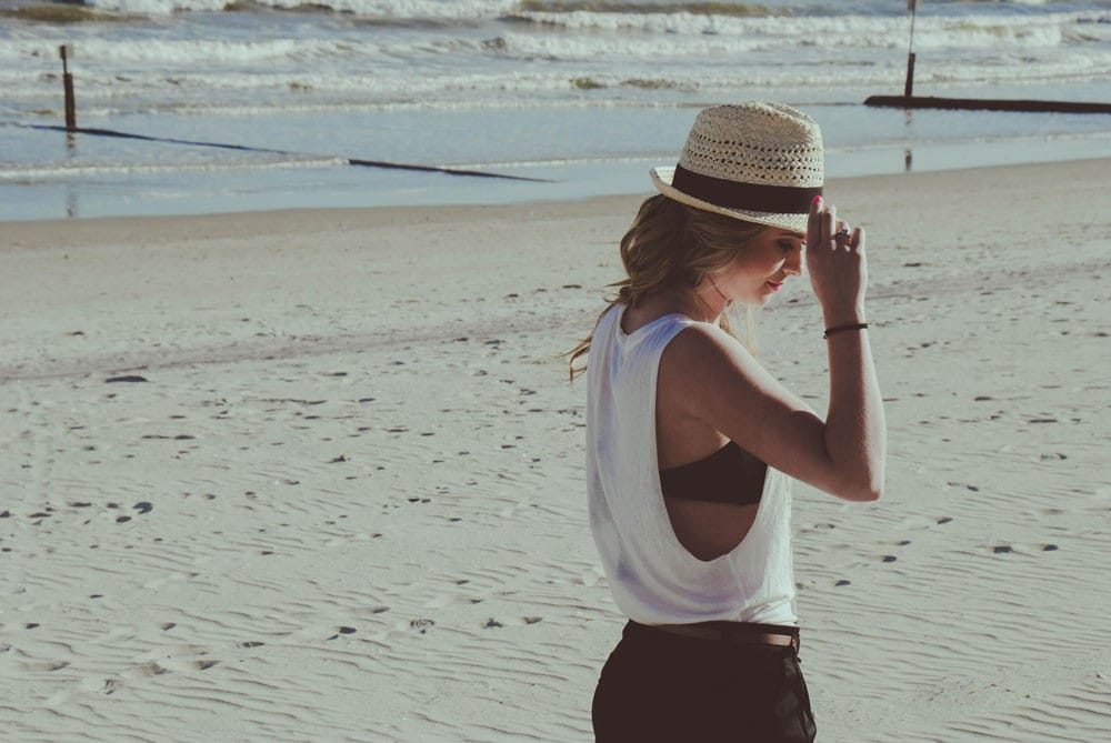 FAQ Australia chica rubia con un sombrero andando por la playa
