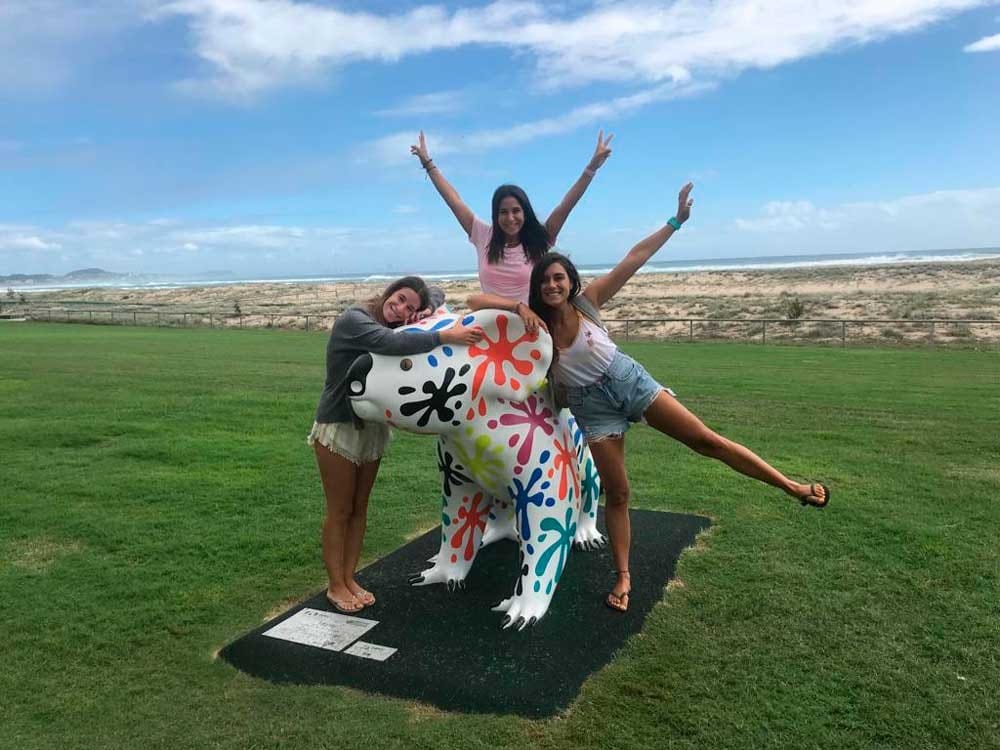 tres chicas encima de una figura de un animal sonriendo a cámara