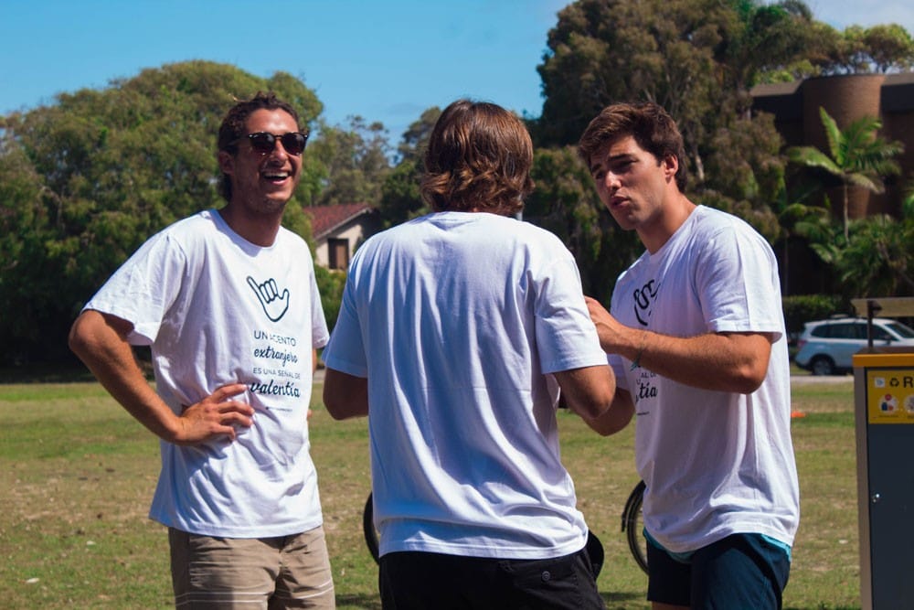 grupo de tres chicos jóvenes con la camiseta de YouTOOProject, riendo y están de pie en el césped.
