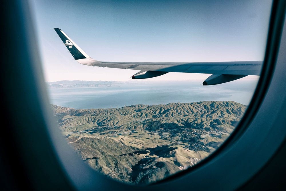 viajar a Nueva Zelanda ventana de un avión y se ve el paisaje de montañas