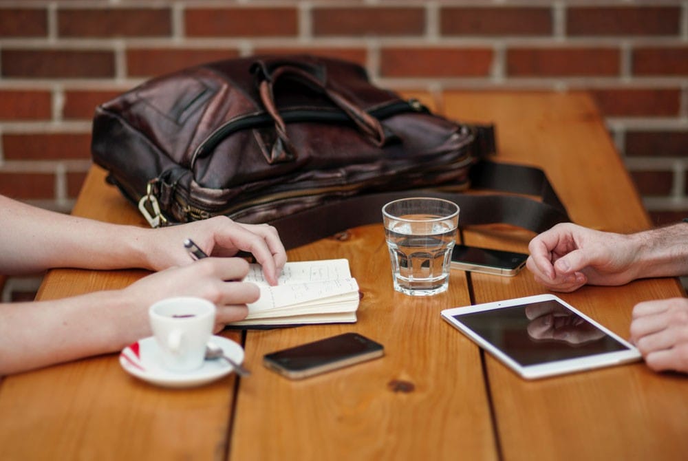 Visados en Canadá chico y chica en una mesa de madera con un bolso encima y un café
