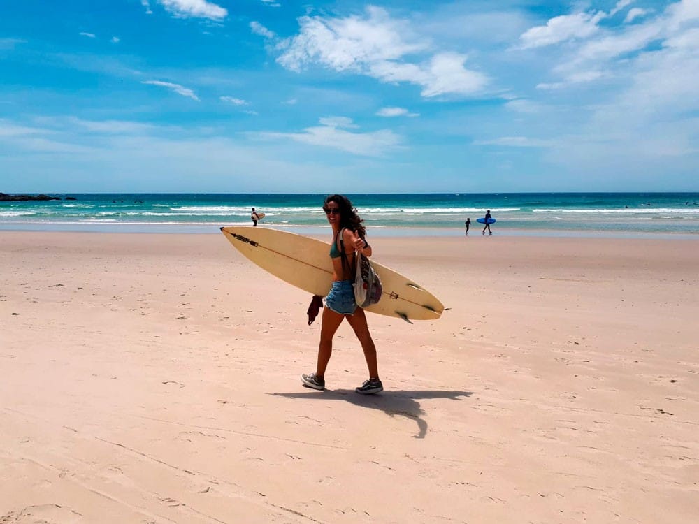 Estudiar en Imagine Education chica con tabla de surf en la playa