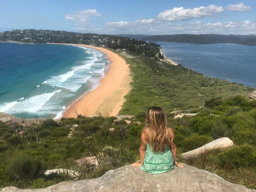 Estudiar en Sydney chica rubia de espaldas y delante el mar y vegetación
