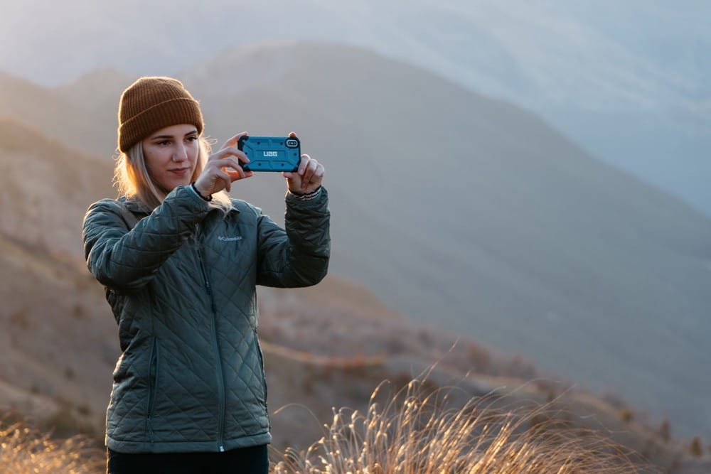 viajar a Nueva Zelanda chica rubia haciendo una fotografía con el teléfono