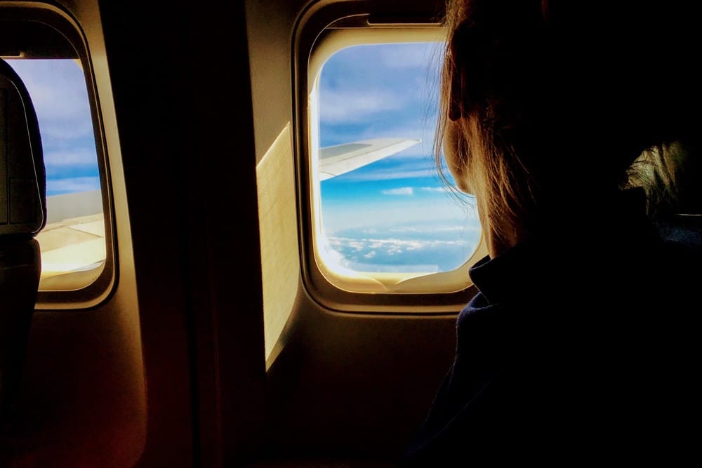 imagen de una mujer mirando por la ventana de un avión